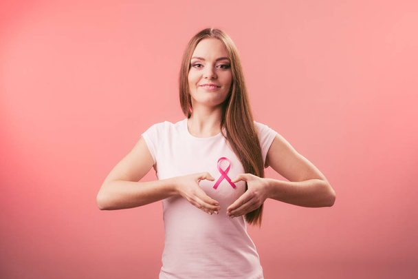 Breast cancer. Woman making heart shape on pink ribbon - Fotoğraf, Görsel