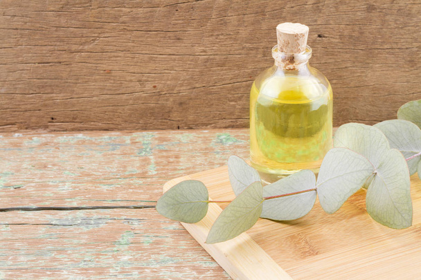 Eucalyptus oil and leaves on wooden table - Foto, Bild