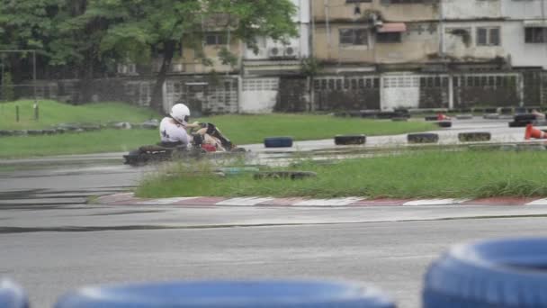 Karting - conductor en casco en el circuito de karts. Adulto Kart Racer en la pista. Clima lluvioso en la pista de carreras. Movimiento lento
 - Metraje, vídeo
