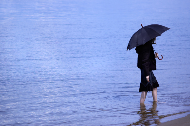 Girl with umbrella on the blue water background - Valokuva, kuva