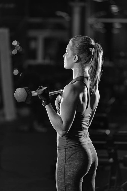 Young woman lifting the dumbbells - Foto, afbeelding
