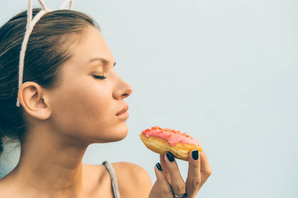 Σέξι μελαχρινή κυρία φάτε γλυκιά καρδιά σχήμα ντόνατ. - Φωτογραφία, εικόνα