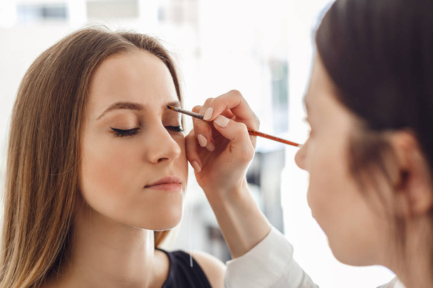 Beautiful young woman gets eyebrow correction procedure. - Фото, изображение