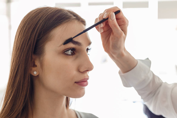 Portrait of a beautiful model during an eyebrow correction procedure - Фото, зображення