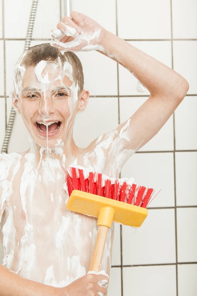 Happy child covered in soap with large scrub brush - Photo, Image