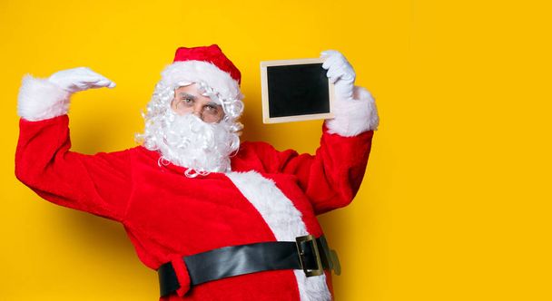 Funny Santa Claus sosteniendo tablero negro
  - Foto, imagen