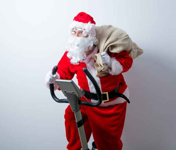 Santa Claus have a fun with Exercise Bikes - 写真・画像