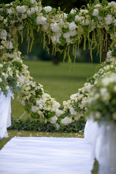 Hart frame gemaakt van mooie bloemen. Boog gemaakt voor huwelijksceremonie - Foto, afbeelding