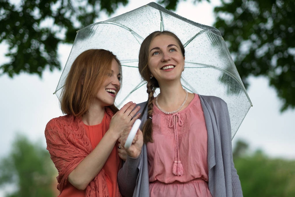 Two women walking park in rain and talk. Friendship and people communication. - Foto, Bild