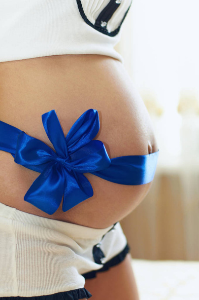 vientre de la mujer embarazada con una cinta azul
 - Foto, Imagen