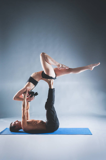 Young couple practicing acro yoga on mat in studio together. Acroyoga. Couple yoga. Partner yoga. - Foto, afbeelding