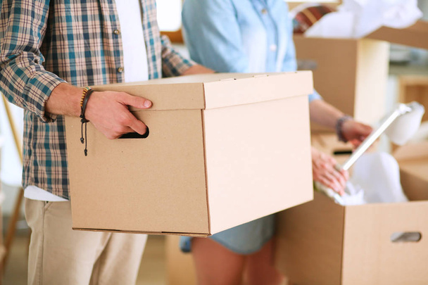 Giovane coppia che trasporta una grande scatola di cartone in una nuova casa. - Foto, immagini