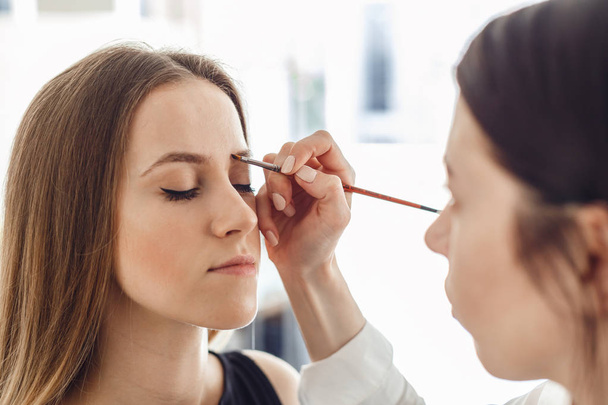 Beautiful young woman gets eyebrow correction procedure. - Foto, Imagen