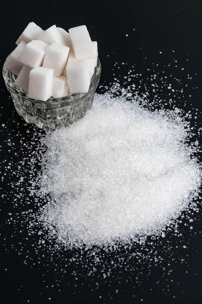 white granulated sugar in bowl and refined sugar on black backgr - Photo, Image