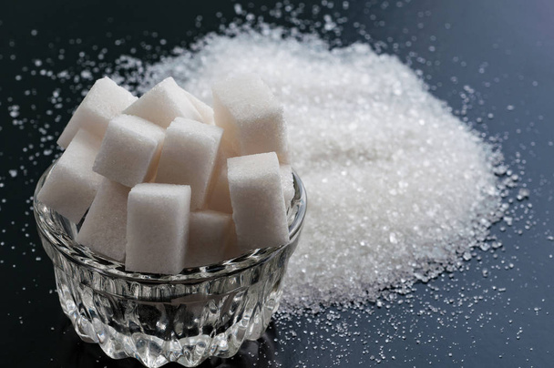 zucchero bianco raffinato e zucchero semolato da vicino sul dorso nero
 - Foto, immagini