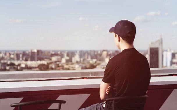 Young man on the roof of a tall building - Foto, Imagen