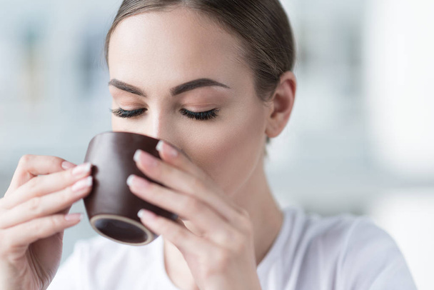 Beautiful woman with fresh make-up resting with hot beverage - 写真・画像
