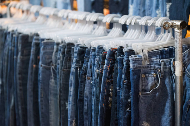 Row of Jeans and trousers on hangers for sale. - Photo, Image