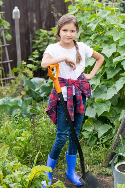 Усміхнена молода дівчина працює в саду з лопатою
 - Фото, зображення