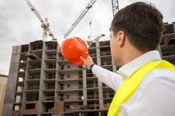 Young construction engineer pointing at building under construct - Photo, Image