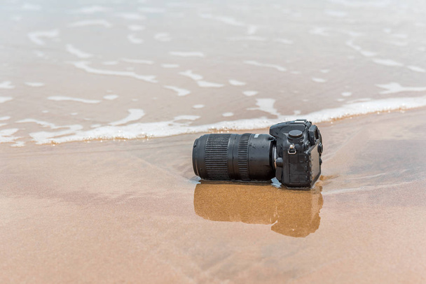 それは海の波から濡れているビーチの上にカメラ - 写真・画像