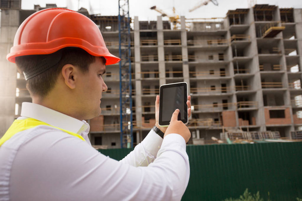 Jeune ingénieur de construction utilisant tablette numérique sur le siège du bâtiment
 - Photo, image