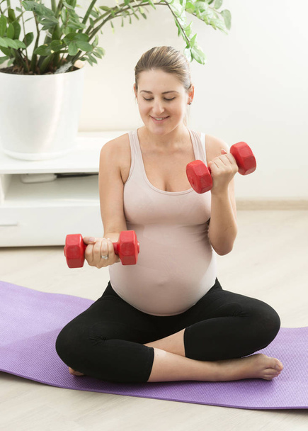 Mujer embarazada haciendo ejercicio con pesas en casa
 - Foto, Imagen