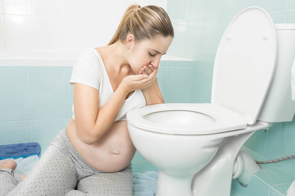Young pregnant woman feeling sick at bathroom - Foto, Imagem