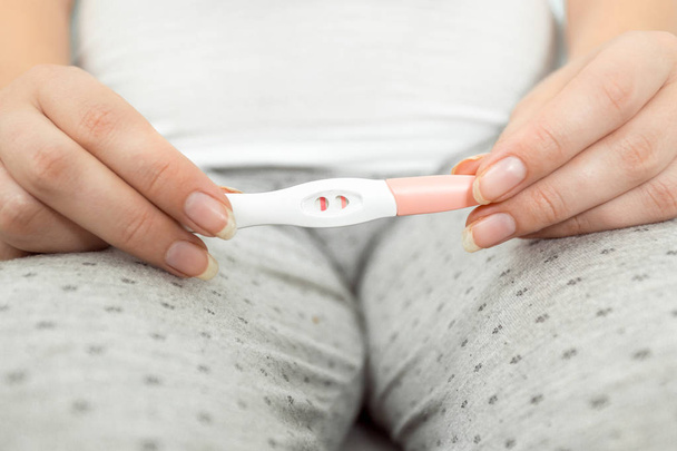 Conceptual photo of woman holding positive pregnancy test at bat - 写真・画像