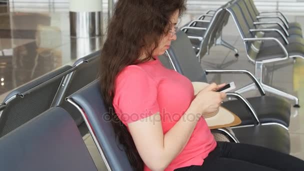 Una giovane donna in aeroporto in attesa di partenza e guardando lo smartphone
 - Filmati, video