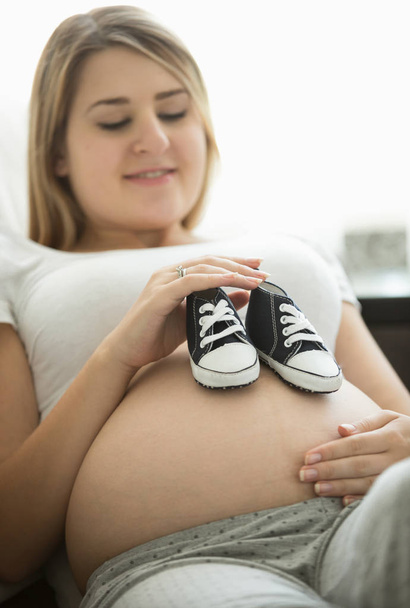 仰向けにソファーと持株赤ちゃん幸せな妊娠中の女性の肖像画  - 写真・画像