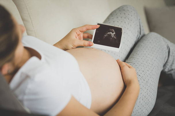 Крупним планом зображення вагітної жінки, дивлячись на ультразвуковий ембріон
 - Фото, зображення