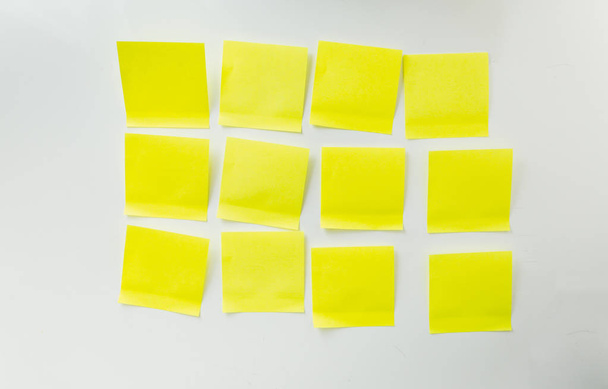 12 puste żółte karteczki na pokładzie biały - Zdjęcie, obraz