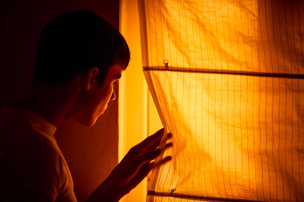 Angstige jonge man staat naast venster - Foto, afbeelding