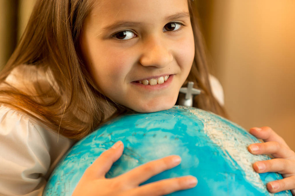 Cute schoolgirl holding big Earth globe - Foto, afbeelding