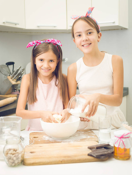 Portrait of two sister mixing ingredients for dough in big bowl - Photo, Image
