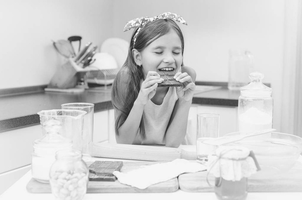 Retrato blanco y negro de linda chica apoyada en la mesa de la cocina a
 - Foto, Imagen