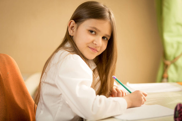 Portrait of smiling brunette girl in white shirt sitting behind  - Foto, Bild