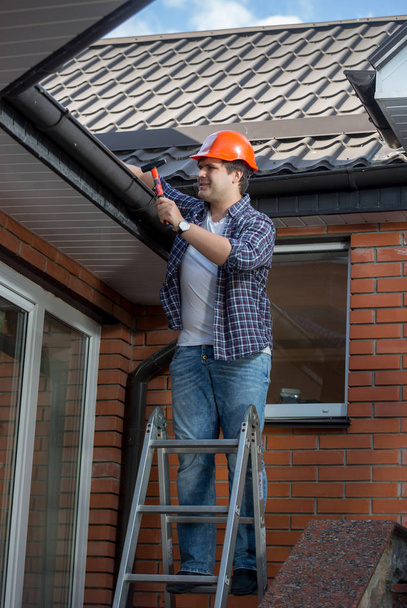 Samec zaměstnance stojí na žebříku krok před domem - Fotografie, Obrázek
