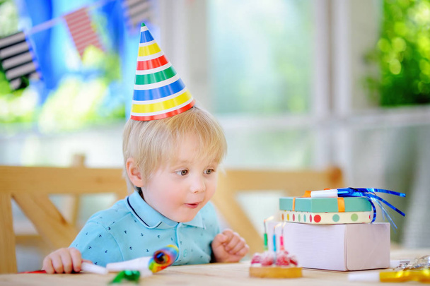 かわいい男の子は、カラフルな装飾とケーキで誕生日パーティーを祝う - 写真・画像