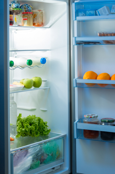 Nyitott hűtőszekrény a konyha este - Fotó, kép