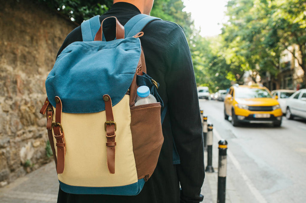 Young male tourist with a backpack in the big city is waiting for a taxi. Journey. Sightseeing. Travel. - 写真・画像