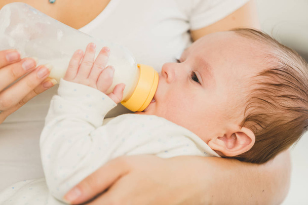 Portrait of 3 months old baby eating milk from bottle - Photo, Image