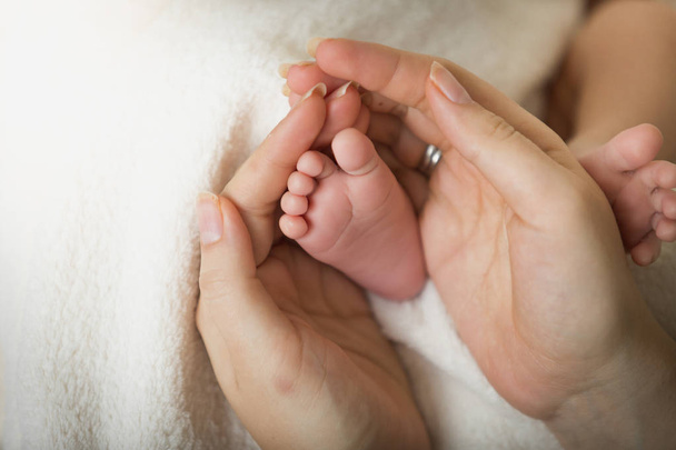 Primer plano de la madre cariñosa sosteniendo los pequeños pies del bebé recién nacido
 - Foto, imagen