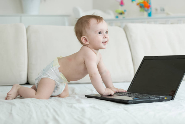 1 roku życia chłopca w pieluchach, indeksowania i docierają do laptopa - Zdjęcie, obraz