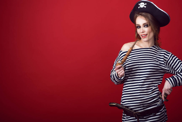 Ritratto di splendida donna con trucco provocatorio che indossa il costume da pirata e il cappello con una pipa di tabacco intagliata in legno, una pistola e un pugnale nella cintura
 - Foto, immagini