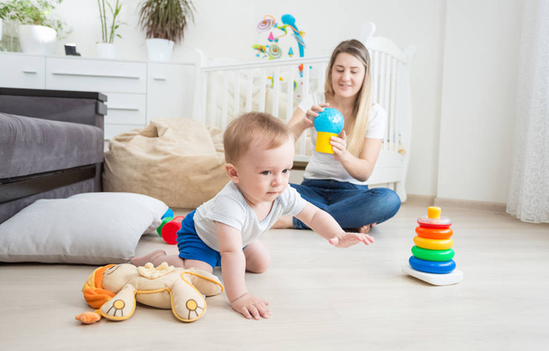 10 maanden oud jongetje spelen op vloer met kleurrijke speelgoed - Foto, afbeelding