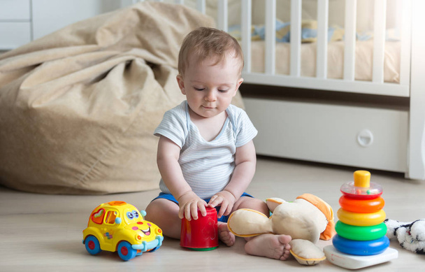 Χαριτωμένο μικρό παιδί αγόρι παίζει με τα πολύχρωμα παιχνίδια στο πάτωμα στο σαλόνι ρ - Φωτογραφία, εικόνα