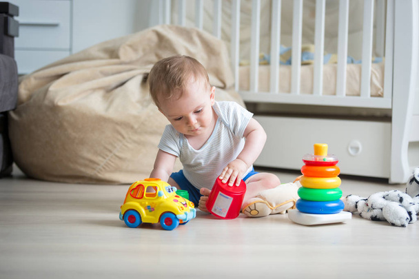 Ładny toddler chłopiec bawi się zabawkami na piętrze - Zdjęcie, obraz