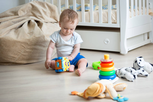 Niño de 9 meses jugando con coche de juguete y torre de juguete
 - Foto, imagen